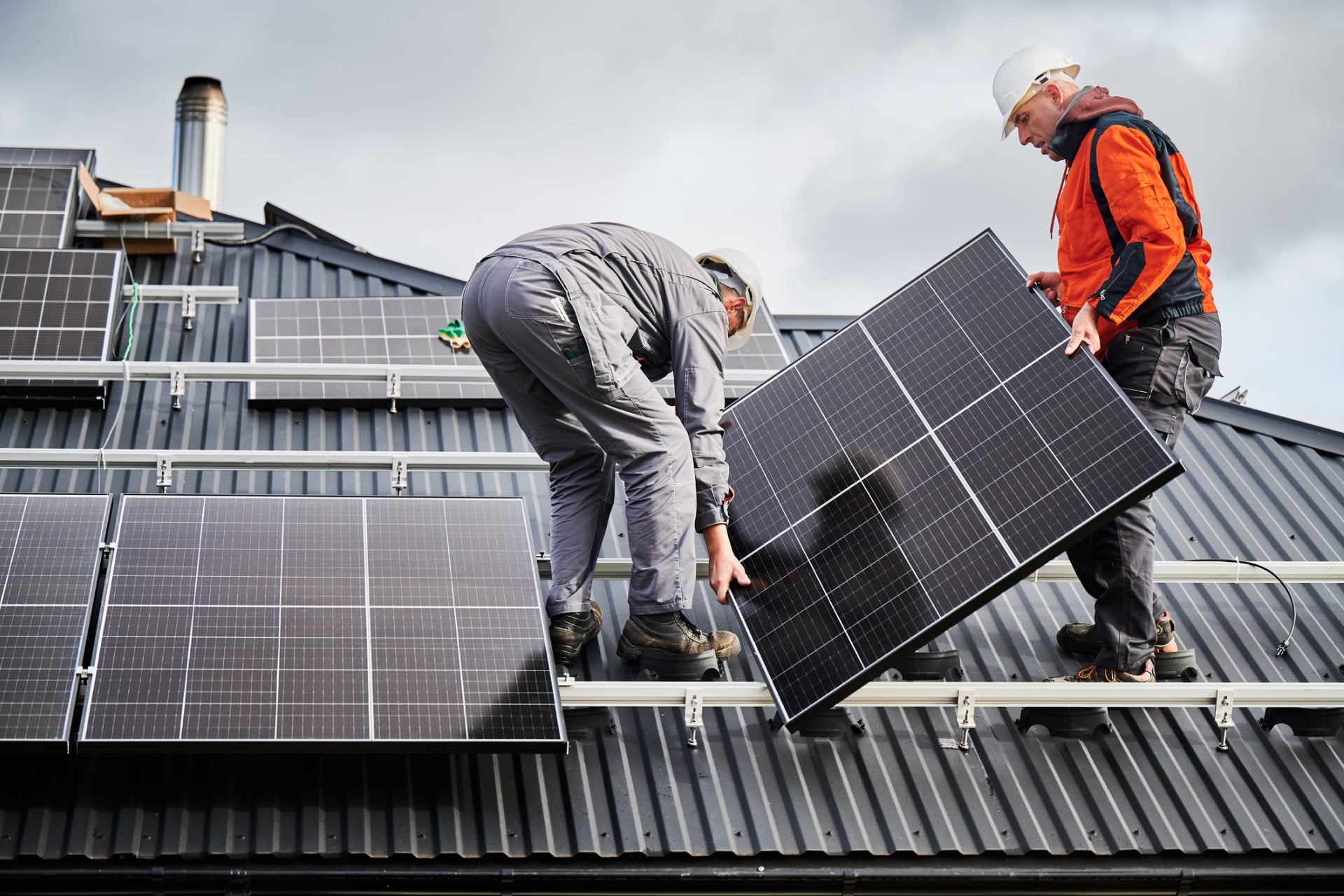 Two technicians installing solar panels on a roof